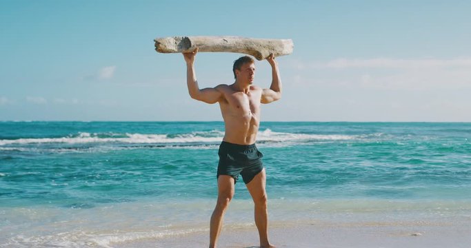 Strong athletic man working out with a beach log, weight lifter achieving his fitness goals