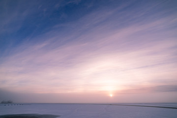Sun through fog at lake winter morning