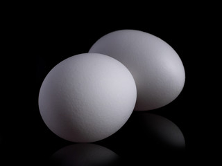 White organic chicken eggs isolated on a black background