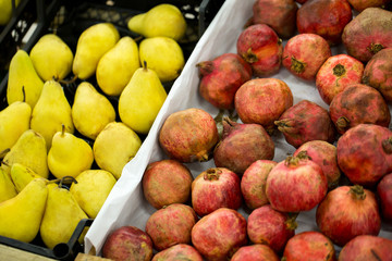 Counter with ripe pomegranates and pears in supermarket
