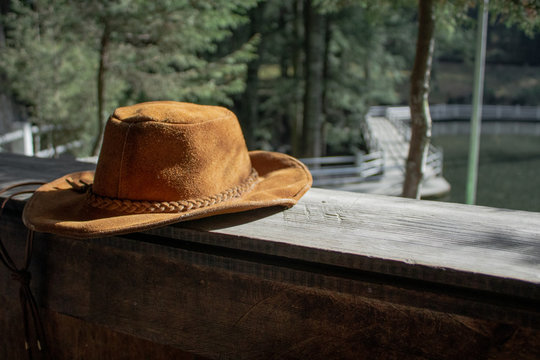 Sombrero color caf&eacute; sobre la tarima de una caba&ntilde;a con vista hacia el bosque