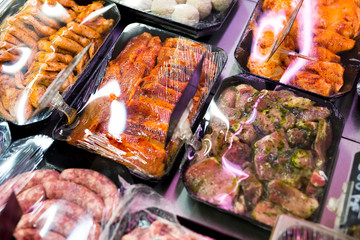 Meats in marinade on supermarket display, pre-cooked food