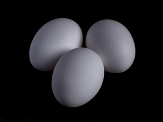 White organic chicken eggs isolated on a black background