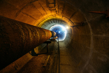 Round concrete underground tunnel of heating duct system with rusty pipes