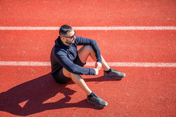 Athletes walk and stretch on the red wet track of athletics, which is a rubber artificial track for...