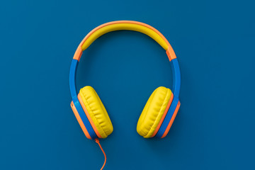 Multi-colored headphones on blue background. Minimalistic fashion music concept. Trendy color of...