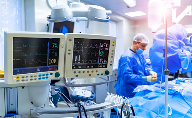 Ecg patient's condition on the monitor in operating room. Surgeon performing operation in operation theater.