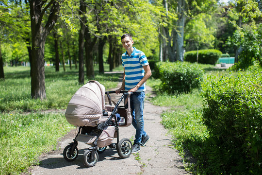 young man walking in an autumn park with a baby stroller