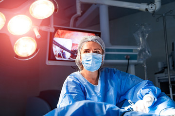 Portrait of the professional medical assistant in surgical mask during operation. Modern hospital...