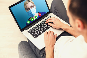 Man having video chat with doctor on laptop at home
