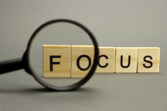 The word focus is made of wooden letters with a magnifying glass. Selective focus