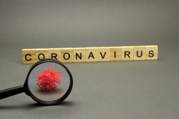 Inscription coronavirus in wooden letters on grey background and crown model. Dangerous 2019-nCov flu infection. Selective focus