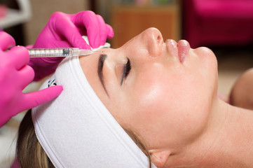 Obraz na płótnie Canvas Beautician doctor hands doing beauty procedure to female face with syringe. Cosmetic medicine and surgery, beauty injections concept