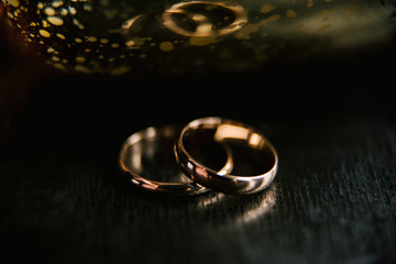 Obraz na płótnie Canvas Elegant wedding rings for the bride and groom on a black background with highlights, macro, selective focus