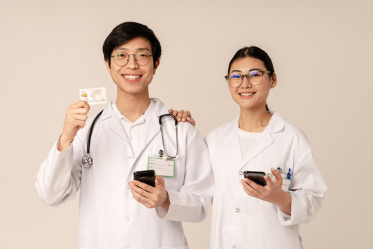 Image of asian young medical doctors holding credit card and cellphone