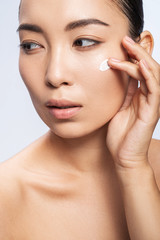 Asian young woman with cosmetic cream on her cheek