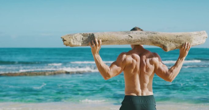 Strong athletic man working out with a beach log, weight lifter achieving his fitness goals