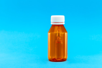 orange plastic bottle with a yellow cap and an ampoule with a vaccine inside, medical concept on a blue background with copy space.