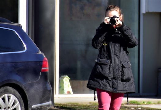 girl with a camera takes pictures on a city street