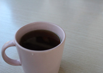 a Cup of tea on a beige table and people sit at the table