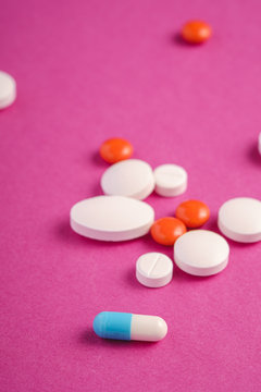 Pills and tablets on bright pink purple background, healthcare medical concept, antibiotics and cure, angle view