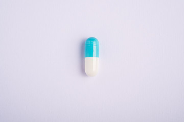 Single blue pill on bright white background, healthcare medical concept, antibiotics and cure, top view copy space