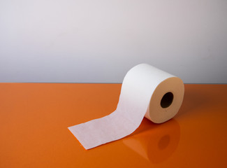 View of a white toilet paper roll over an orange background
