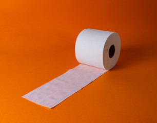 View of a white toilet paper roll over an orange background