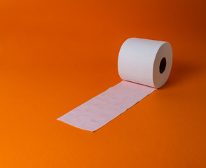 View of a white toilet paper roll over an orange background