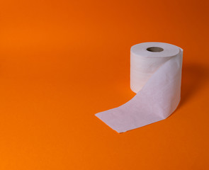 View of a white toilet paper roll over an orange background