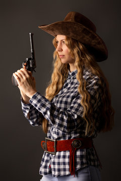 Lovely blonde posing in studio with a cowboy hat and a gun