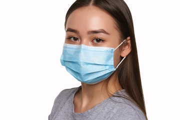 Close up portrait of a young chinese girl on an isolated white background in a protective mask, looking to the camera. Protection against SARS and viruses.