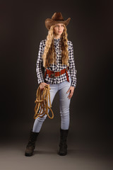 Lovely blonde posing in studio with a cowboy hat and a rope.
