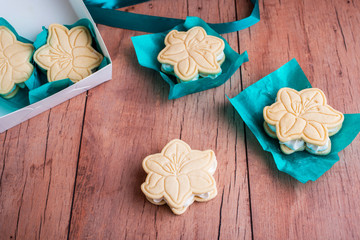 Shortbread cookies with meringue in the form of a flower, on a light wood background.