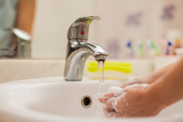 Woman washing hands with soap in bathroom. People and healthcare concept.