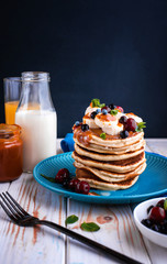 Delicious pancakes with banana, berries, mint and salted caramel in a plate.