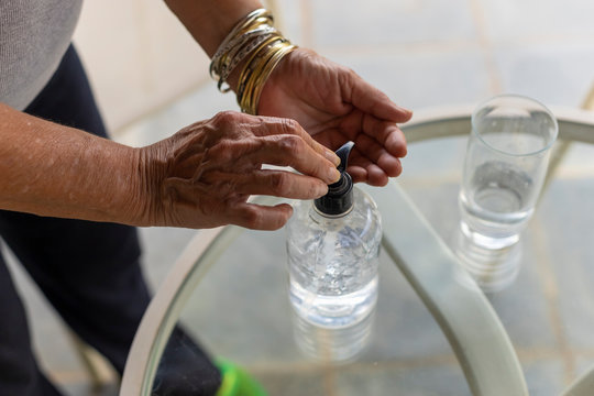 Mulher Idosa Igienizando As Mãos Com álcool Gel