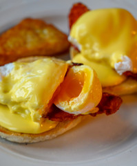 Weekend brunch in Scotland with two eggs benedict on homemade muffuns with roasted bacon and yellow hollandaise sauce.
