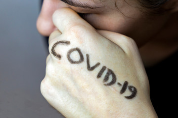 Girl rubbing eyes with hands with covid-19 written on it. Stop spreading virus. Don't touch eyes with dirty hands