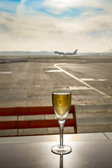 Glass of champagne on a table in an airport business lounge with an aircraft taking off burred in the background