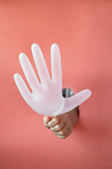Hole in the paper, trend. Space for text. Pink paper and a disposable medical glove. Safety and hygiene.