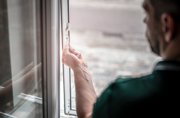 freundlicher Handwerker montiert Insektenschutzgitter bei einem Kunden zu Hause