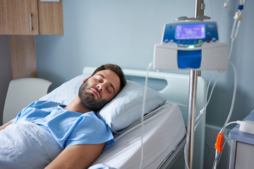 Man attached to an intravenous drip sleeping in a hospital