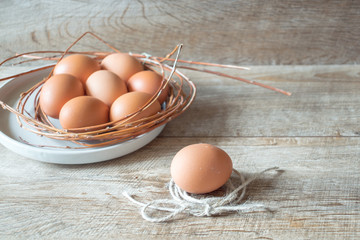 Brown eggs on a plate on wooden table. Easter mockup on rustic background with copy space.