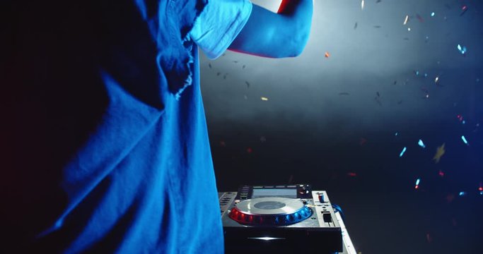 Rear view of cool dj performing in a nightclub, dancing at mixer controller and cheering the crowd up - nightlife concept 4k footage