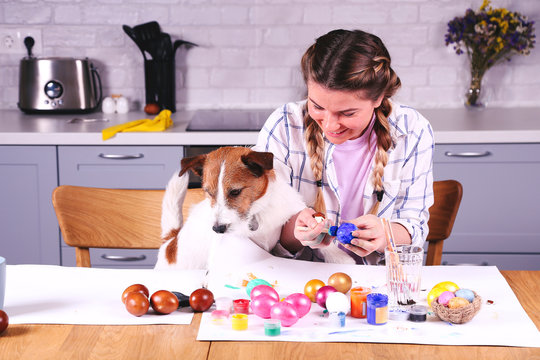 Girl and dog painting easter egg.