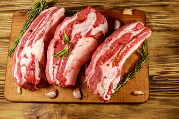 Raw pork ribs with spices, garlic and rosemary on wooden table. Top view