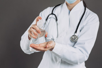 Doctor wearing surgical face mask holding showing alcohol gel pump bottle. Washing hands with alcohol gel or antibacterial soap sanitizer. Covid-19 or Coronavirus concept.