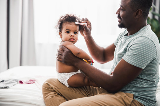 Smiling Father Combing Hair Of Newborn Daughter