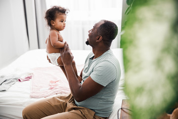 Afro American man holding adorable baby girl in arms